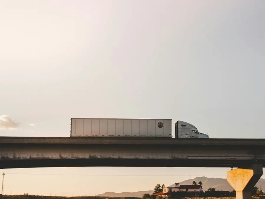 A freight truck on a highway overpass at dusk, the operations Eranova embeds in